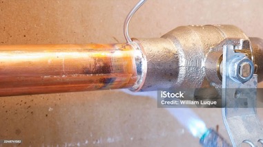 Ett kopparrör som löds med låga vid en rörkoppling